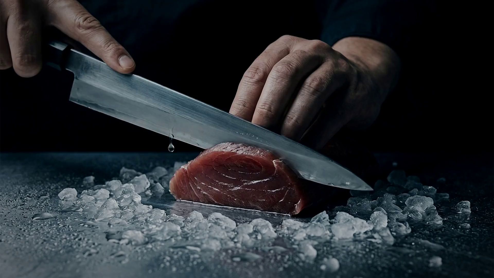 A chef slicing raw tuna on crushed ice, the first of KOMI's four techniques.