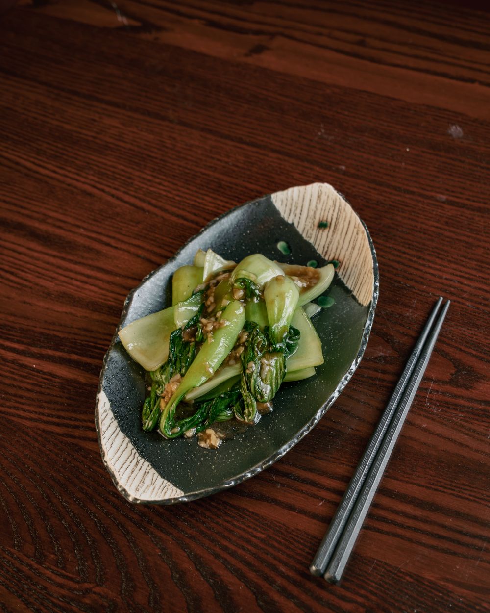 Pak choi with garlic and soy on a dark leaf-shaped plate.